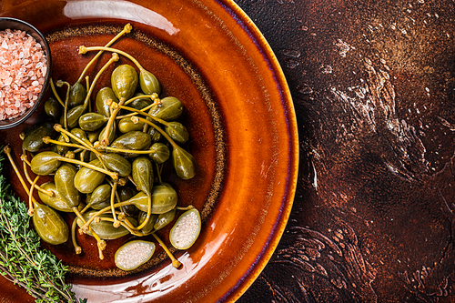 Pickled  Capers berries in a rustic plate. Dark background. Top view. Copy space.