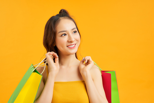 Portrait of happy Asian pretty girl holding shopping bags look at away isolated over blue background, black friday season sale,colorful shopping summer sale concept.