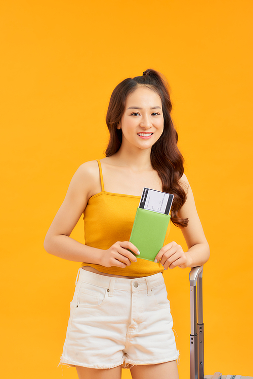 concept of travel. happy woman girl with suitcase and passport on orange colored background