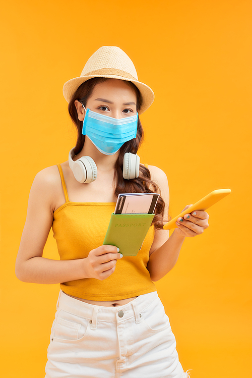 Young women wearing face mask for protection coronavirus in studio using smartphone and holding passport
