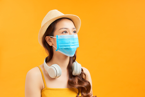 Portrait of young traveller girl wearing face mask over orange background.
