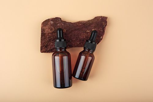 Two dark transparent glass bottles with skin serum or oil for manicure on dark wooden background with copy space. Concept of organic natural skin care products and beauty serums