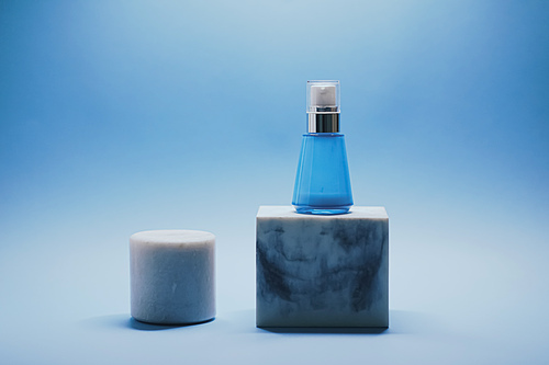 Serum bottle and facial cream jar on blue background, luxury skincare products, beauty and cosmetics.