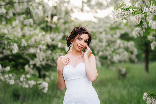 bride in a white dress with a large spring bouquet in a green forest