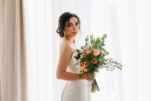 bride in a white dress with a bouquet in a hotel room
