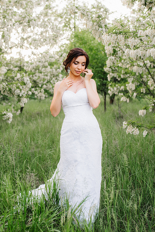 bride in a white dress with a large spring bouquet in a green forest