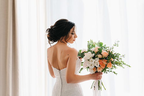 bride in a white dress with a bouquet in a hotel room