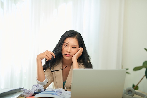 Young Asian worker woman working with laptop computer. A woman thinking of some idea and feeling stress while working from home