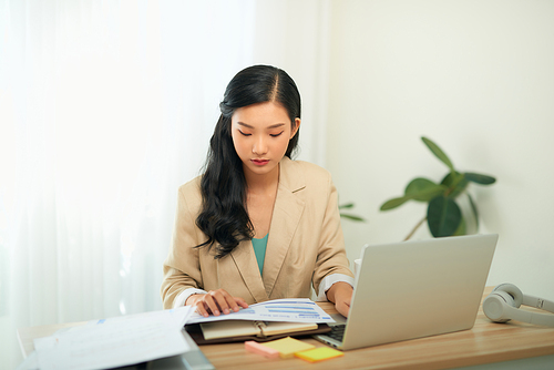 Focused woman journalist freelancer working online on laptop, sitting at desk at home