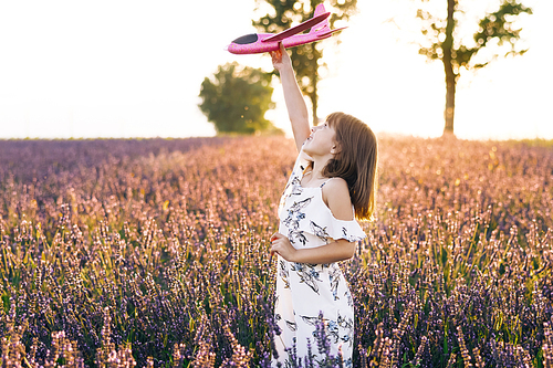 Children play toy airplane. Girl with the airplane in the hands at sunset. Happy girl with a toy airplane on a lavender field in the sunset light. Concept big child dream