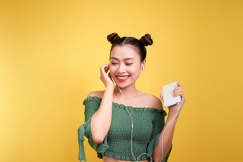 Colorful studio portrait of happy young asian woman with earphones is dancing and singing.