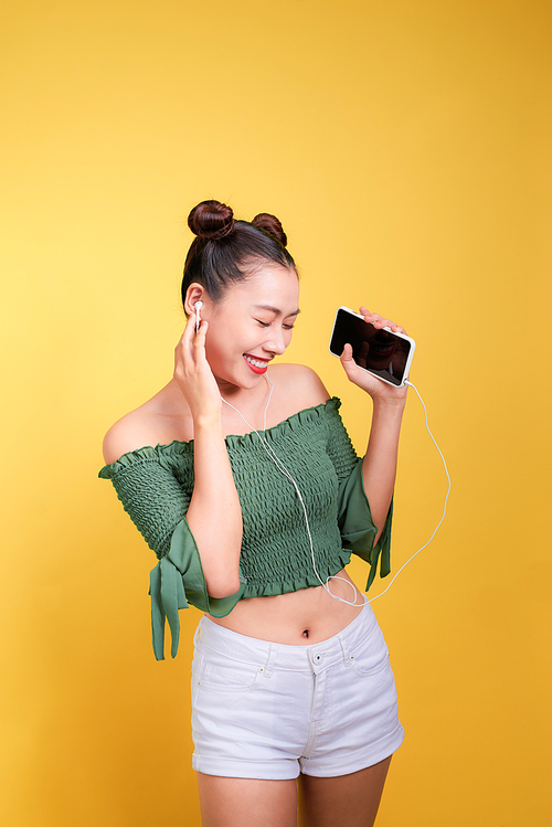 Colorful studio portrait of happy young asian woman with earphones is dancing and singing.