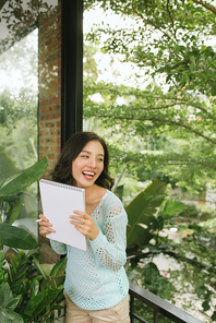 Happy Beautiful Asian Woman holding book or diary on green natural outdoor background.