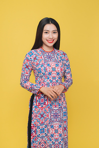 Attractive Vietnamese woman wearing traditional costume, isolated on yellow background