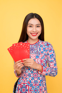 Pretty smiling Vietnamese woman with red envelopes isolated over yellow background