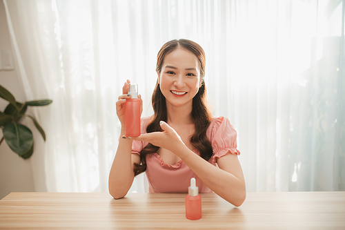 Happy beauty influencer woman showing cosmetics products sitting at home