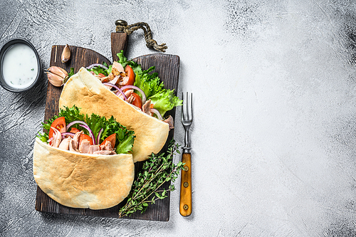 Pita sandwich with roasted chicken, vegetables and delicious sauce. White background. Top view. Copy space.