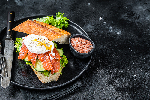 Sandwich toast with Benedict egg, smoked salmon and avocado on bread.  Black background. Top view. Copy space.