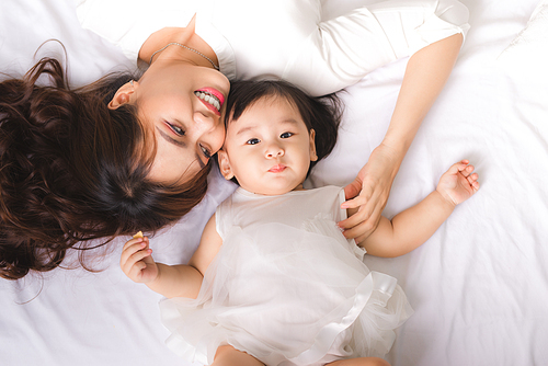 Happy loving family. Mom and child girl are having fun on the bed.