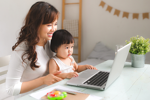 Happy young asian mother and her baby playing games on internet.