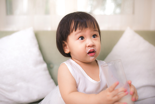 Funny asian child girl drinking yogurt or milk