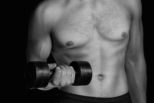 Muscular sportsman exercises with metal dumbbell, fitness, face is not visible. Black and white image