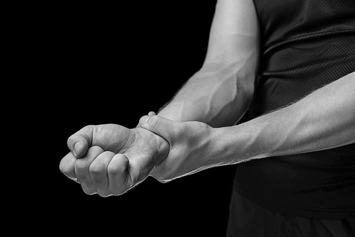 Pain in a male wrist. Man holds his hand, monochrome image