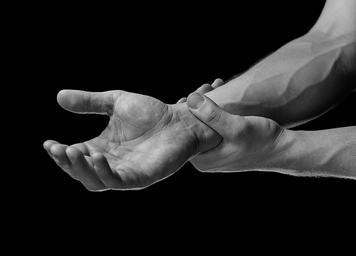 Acute pain in a male wrist. Man holds his hand, black and white image