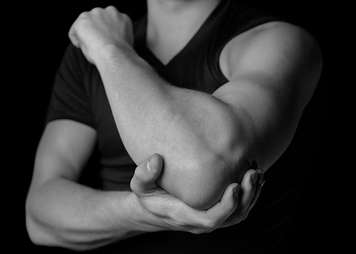 Man holds his the elbow joint, acute pain in the elbow, black and white image