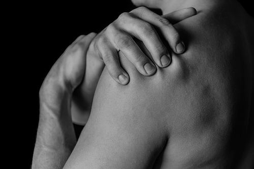 Man compresses his shoulder, pain in the shoulder, black and white image