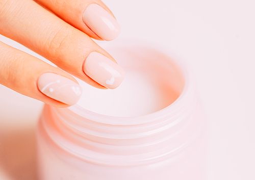 Close-up of female hand using moisturizing cream from jar, concept of beauty and skincare.