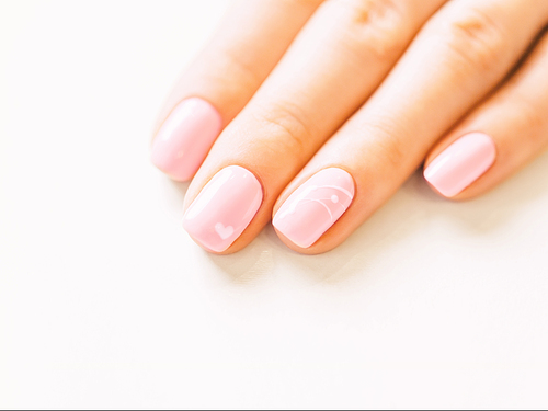 Woman’s hand with professional manicure of pink color and art design. Concept of beauty salon.
