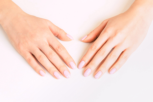 Beautiful female young hands with professional manicure and pink pastel color polish.