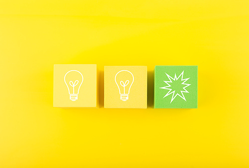 Concept of idea, creativity, start up or brainstorming. White drawn bulbs on yellow and green toy blocks against bright yellow background
