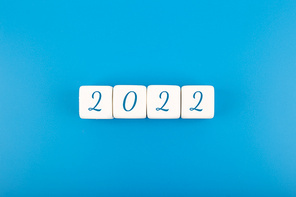 2022 numbers written on white toy cubes in a row as a calendar against bright blue background with copy space. Minimal elegant business style concept of upcoming 2022 year