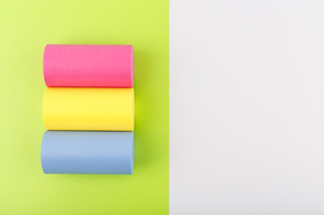 Flat lay with pansexual flag made of pink, yellow and blue rolls on light green and white background with copy space. Concept of pansexual community, sexual minorities, equal right and tolerance
