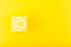 Minimal trendy copyright, intellectual property and patenting concept. Copyright symbol on yellow block against yellow background with copy space