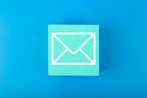 Email marketing, newsletter, promotion information and virtual communication concept. Envelope drawn on toy square against blue background.