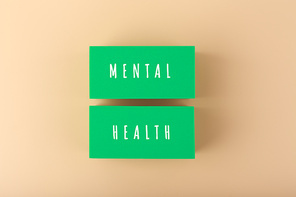 Creative flat lay with green tablets with written mental health text on bright beige background. Concept of world mental health day, mental health assessment and awareness