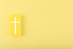 Modern religious minimal concept of hope with christian cross on bright yellow background with copy space. Biblical creative composition with white cross