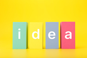 Concept of idea, creativity, start up or brainstorming. Single word idea written on multicolored rectangles in a row on bright yellow background