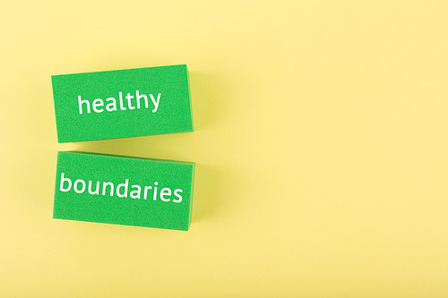 Minimal simple flat lay with green rectangle with written healthy boundaries text on bright yellow background with copy space. Concept of world mental health day, psycology, mental health assessment and awareness