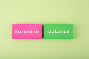 Trendy minimal hormone balance concept in bright green and pink colors. Inscription on multicolored tablets, health care and medical concept.