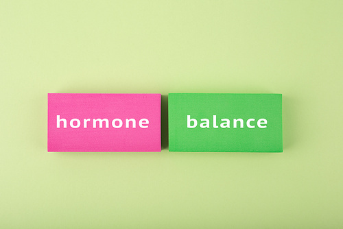 Trendy minimal hormone balance concept in bright green and pink colors. Inscription on multicolored tablets, health care and medical concept.