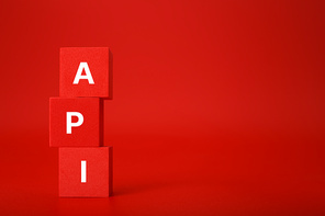 API concept in monochromatic red colors with copy space. API written on stack of red toy cubes. Application program interface