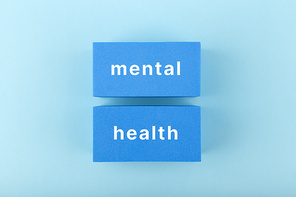 Creative flat lay with blue rectangles with written mental health text on bright pastel blue background. Concept of world mental health day, mental health assessment and awareness