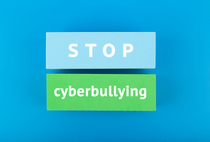 Stop cyberbullying concept. Minimal flat lay with stop cyberbullying inscription on colored rectangles on blue background.