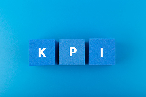 Minimal modern business KPI concept. KPI letters on blue toy cubes in a row against dark blue background with copy space. High quality photo