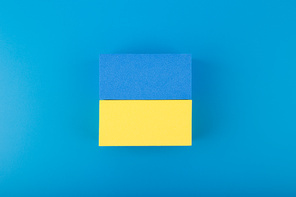 Creative flat lay with national flag of Ukraine made of toy rectangles on dark blue background with gradient.