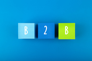 B2B minimal commercial marketing business concept. B2B letters written on multicolored cubes in a row against dark blue background